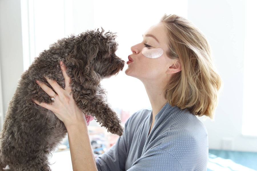 woman kissing a dog on the nose, with smear of product under her eyes